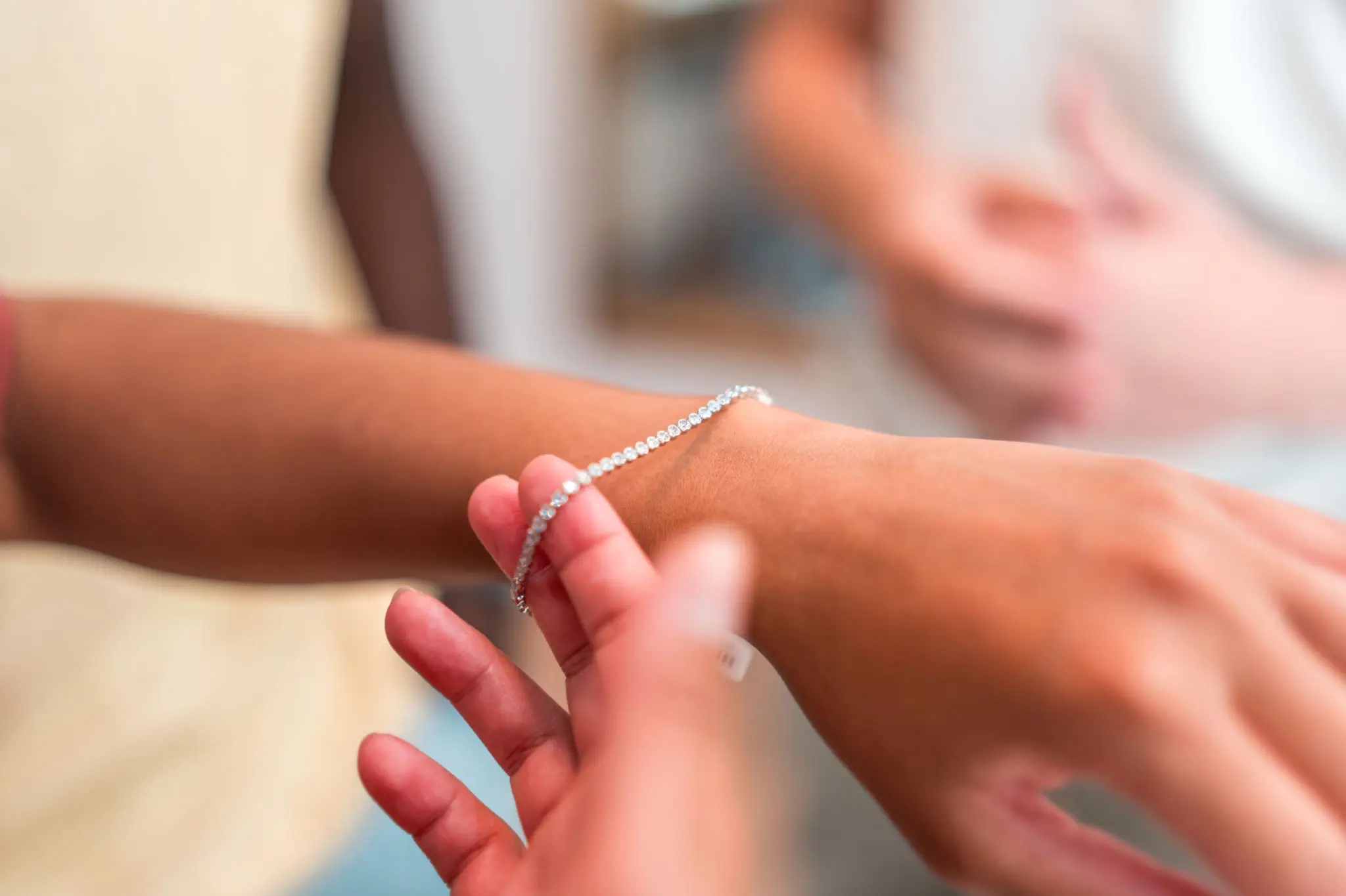 A person tying a bracelet on someone's wrist.
