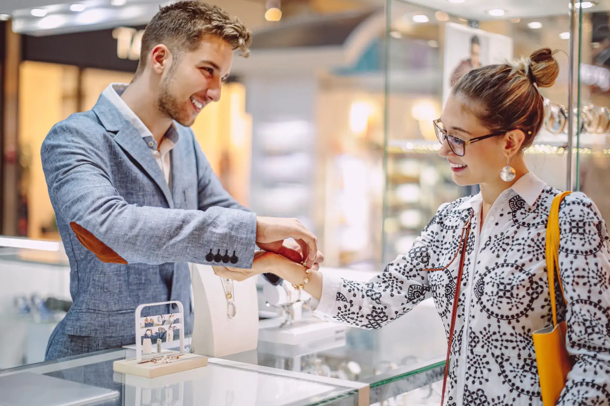 Salesman assisting customer with jewelry fitting at a store.